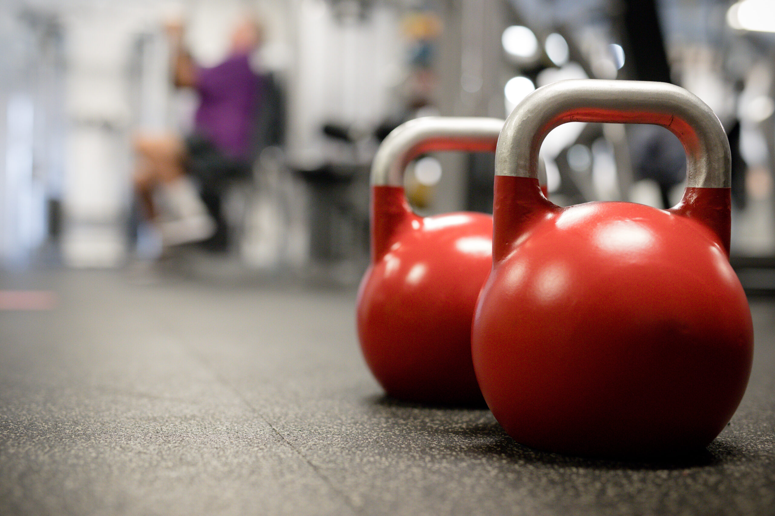 Two red kettlebells sit on the gym floor