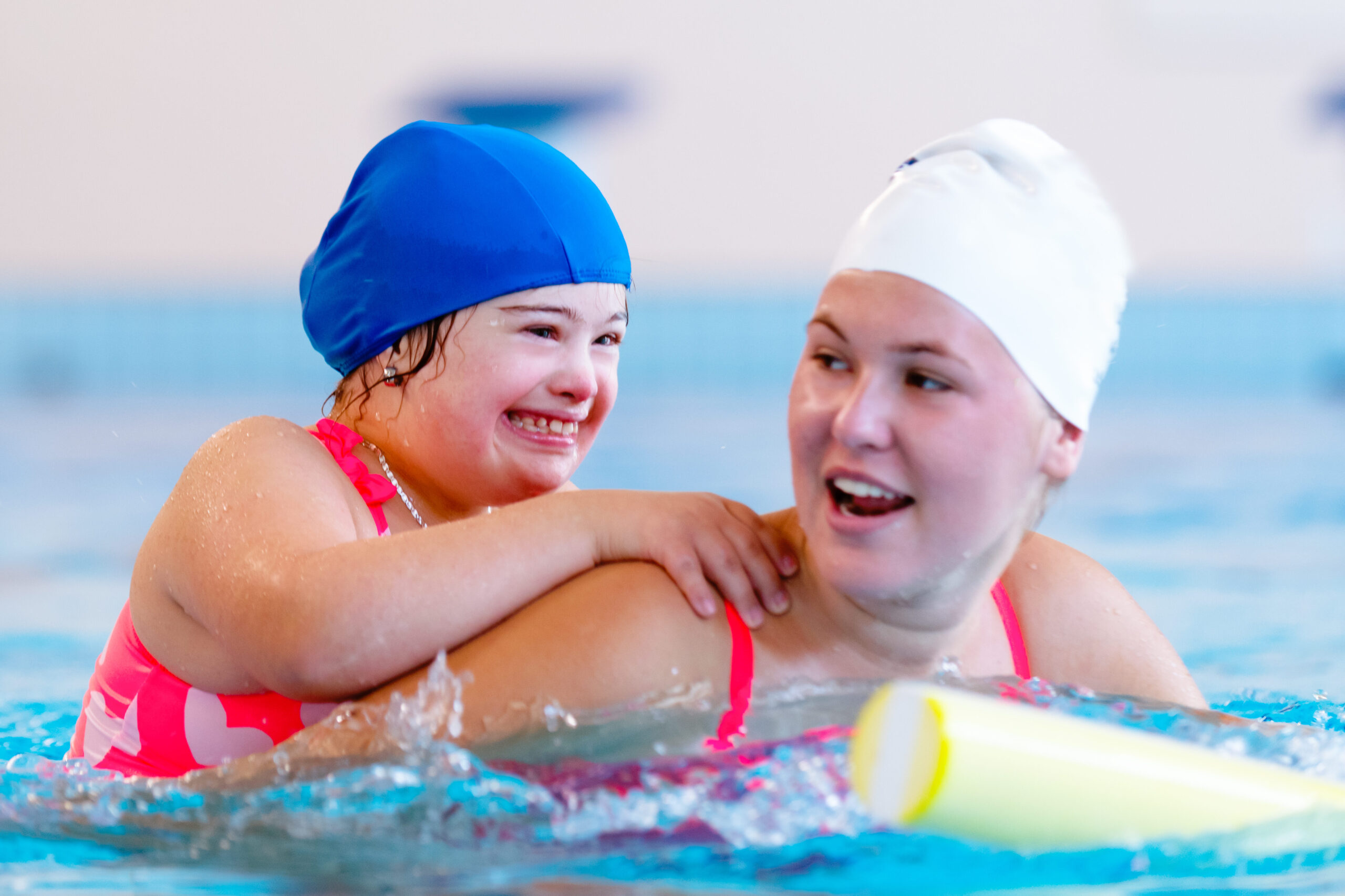 Little girl with Down's syndrome follows a swimming lesson with a coach