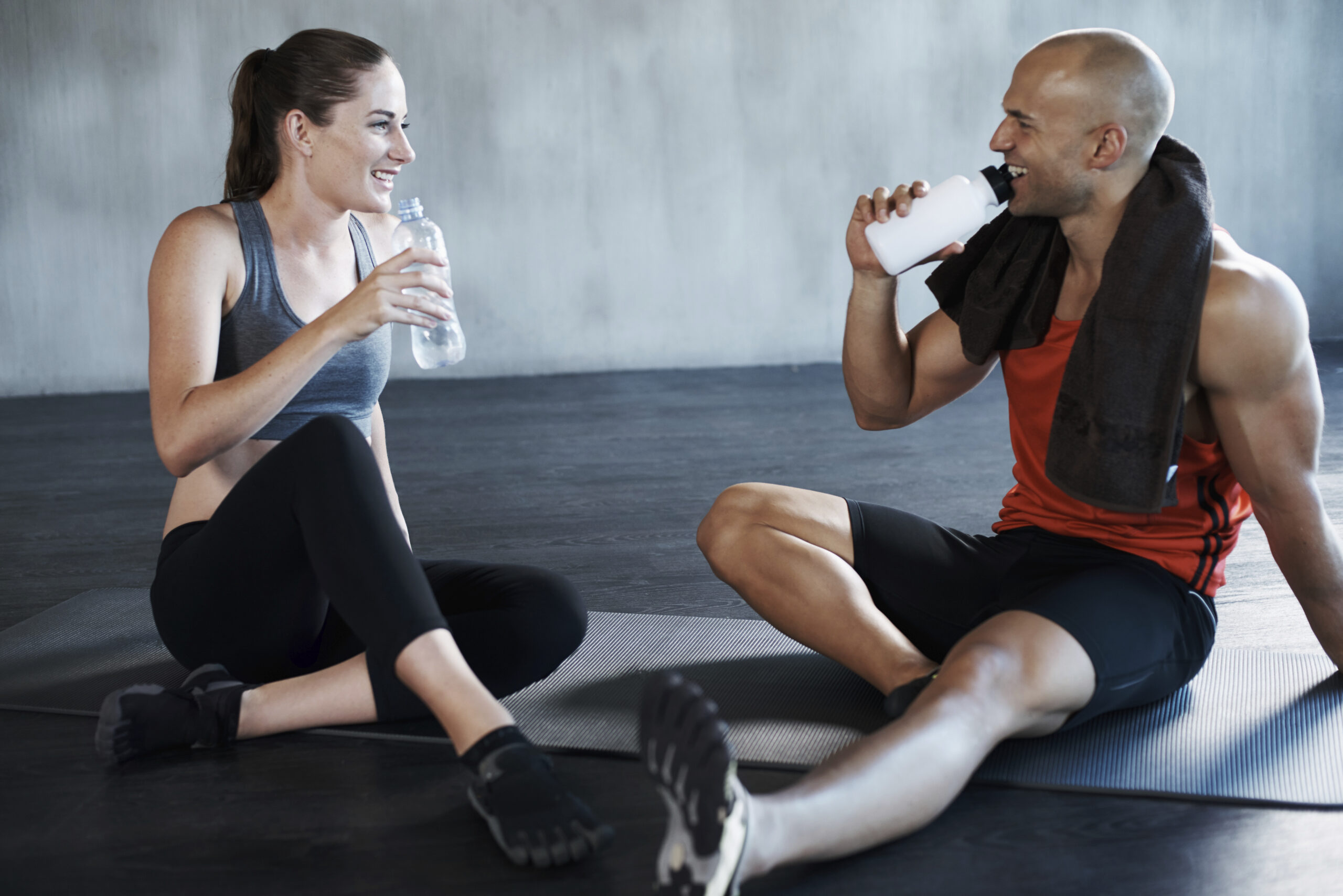 Shot of a young man and woman sitting on the floor in gym gear
